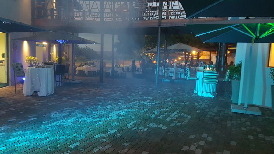 Outdoor dining area with ambient blue uplighting set up for an evening event