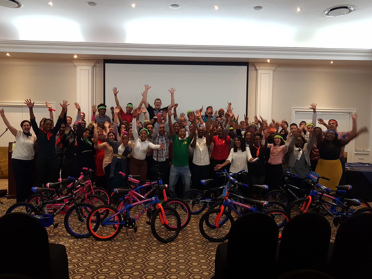 Corporate team celebrating with arms raised after a charity bike build activity
