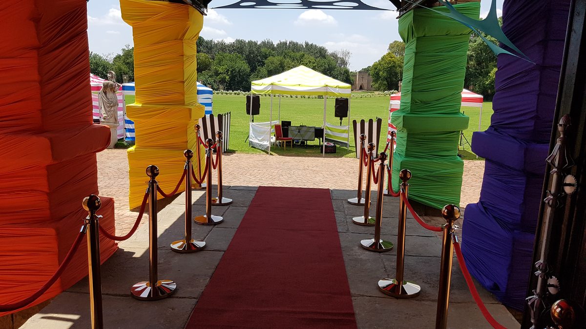 Red carpet entrance with rope barriers and themed pillars at a corporate function