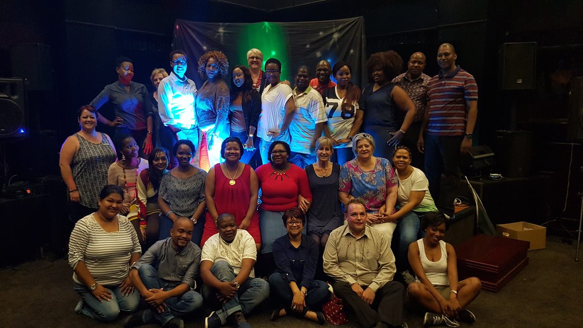 Corporate team posing together on stage under coloured lighting at a staff function