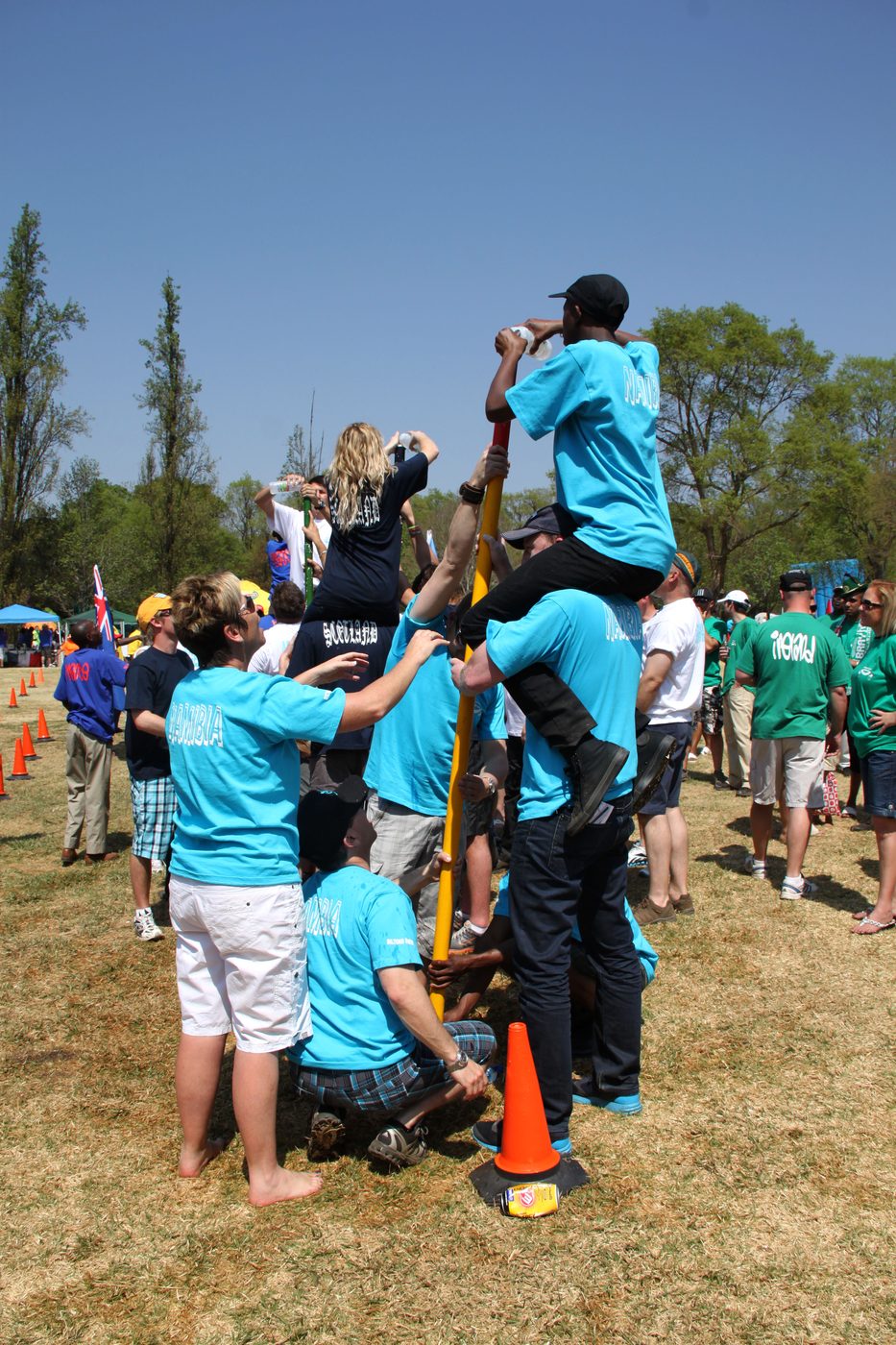 Teams climbing a pole together during an outdoor team building challenge